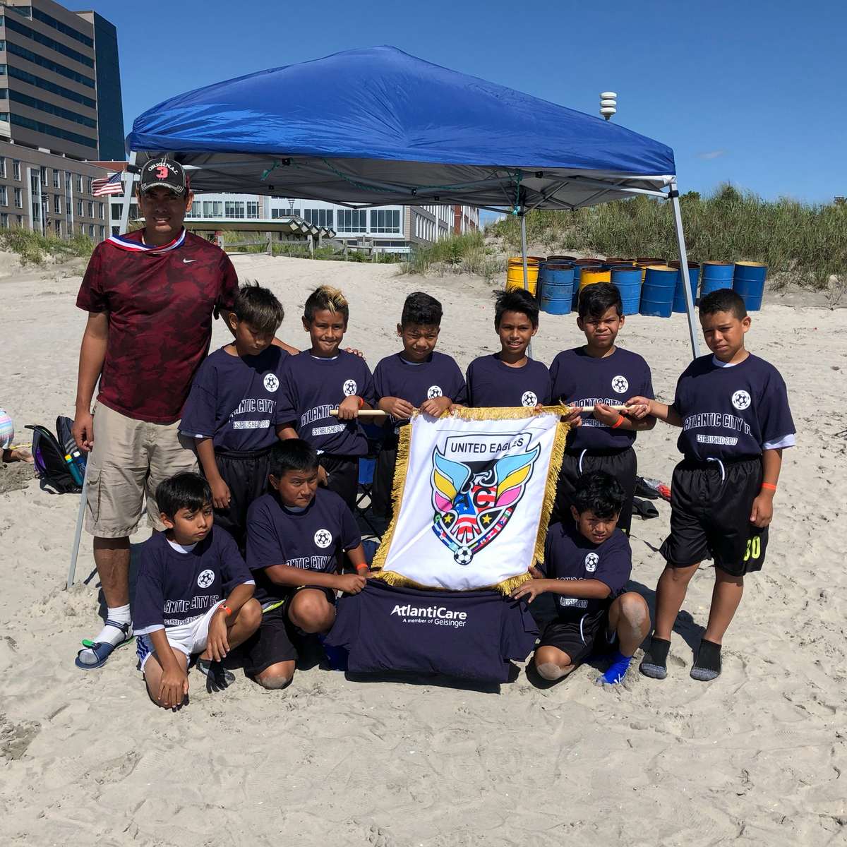 A youth team on the beach with their banner